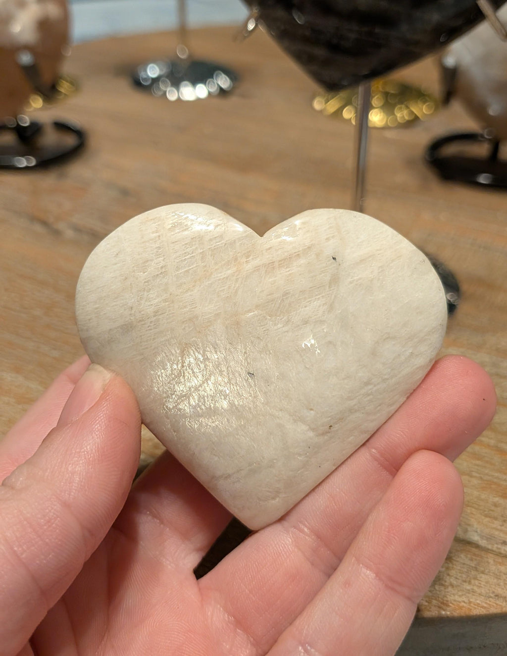 "Detailopname van een gepolijst maansteen hart met een zachte perzikkleurige glans en natuurlijke veldspaat lijnen."