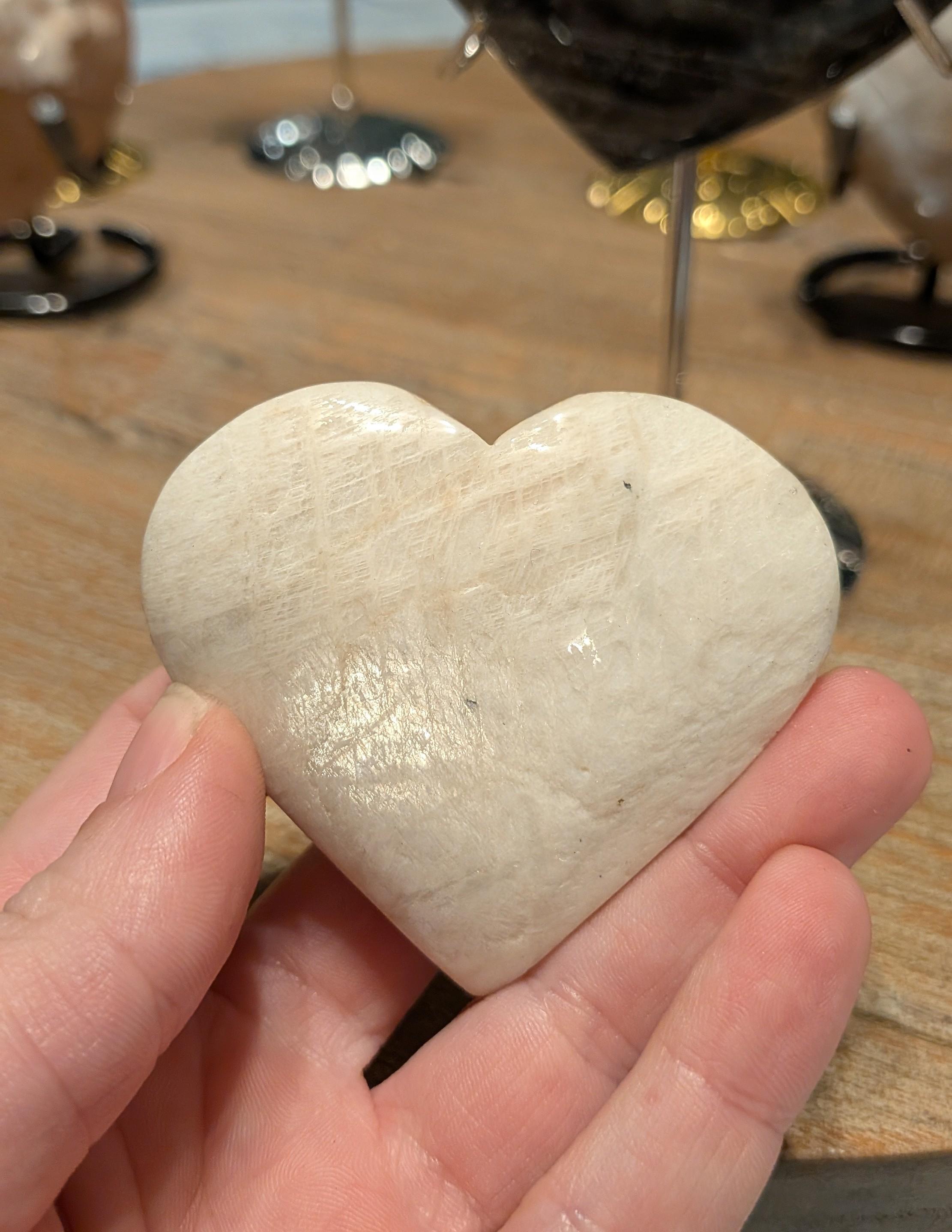 "Detailopname van een gepolijst maansteen hart met een zachte perzikkleurige glans en natuurlijke veldspaat lijnen."