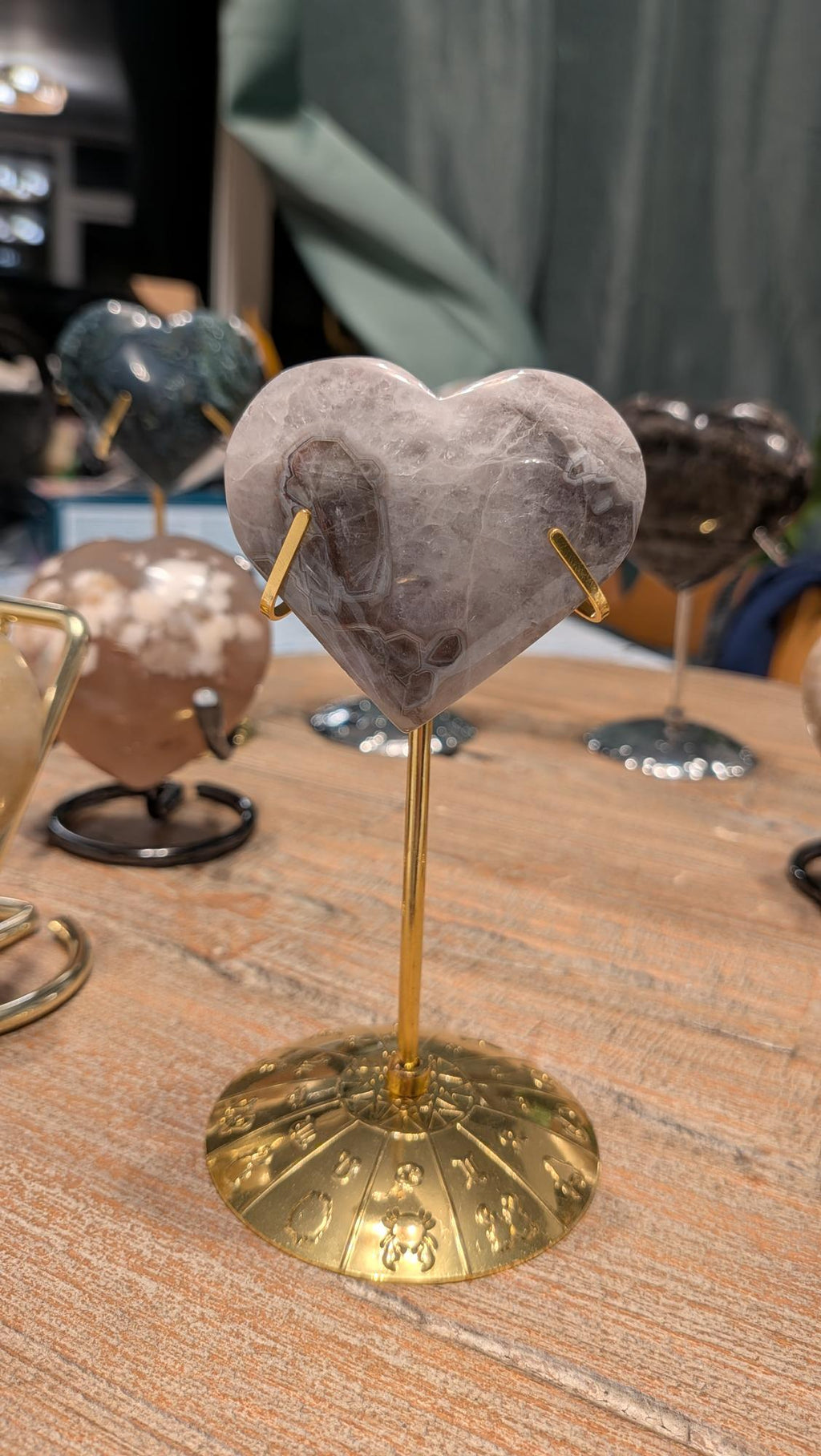 "Chevron amethist hart van 85 gram met paars-witte patronen op een goudkleurige standaard met gegraveerde dierenriemtekens."