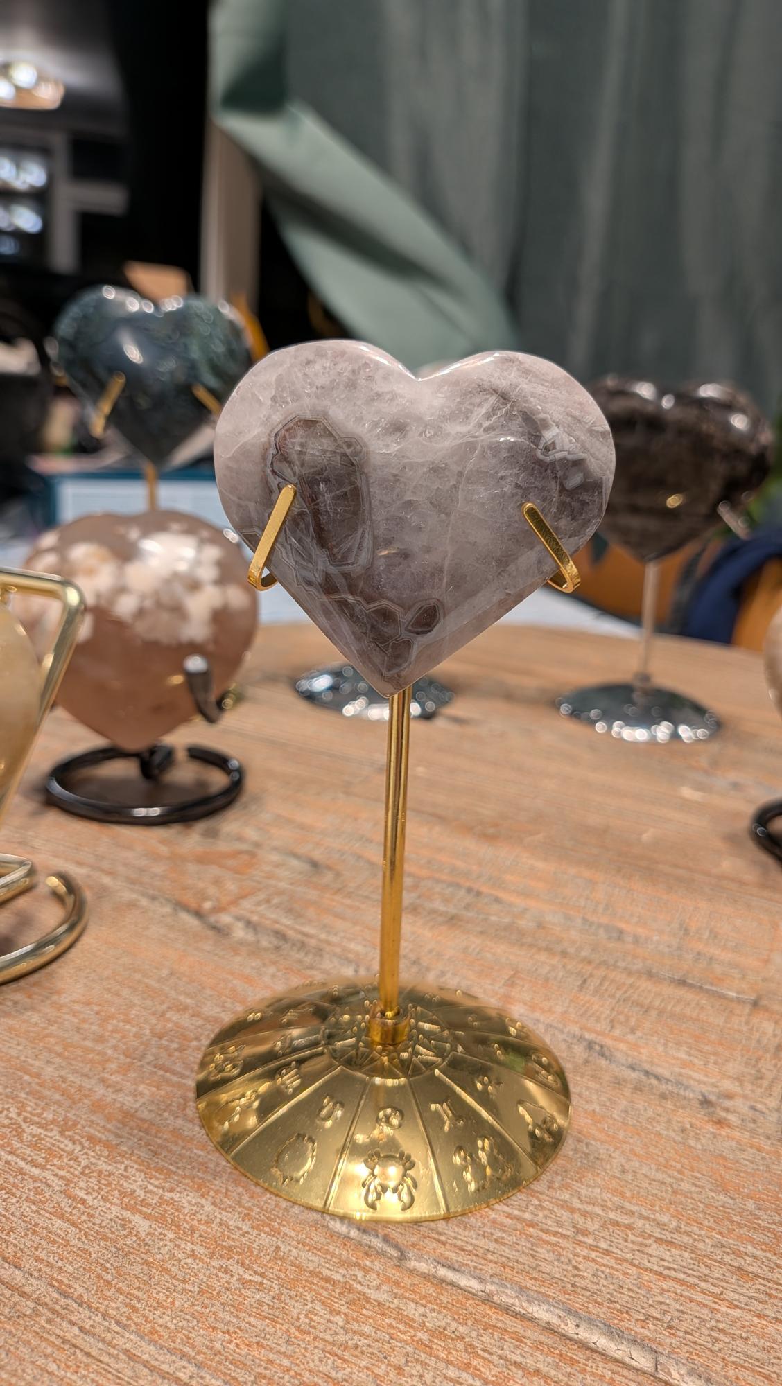 "Chevron amethist hart van 85 gram met paars-witte patronen op een goudkleurige standaard met gegraveerde dierenriemtekens."