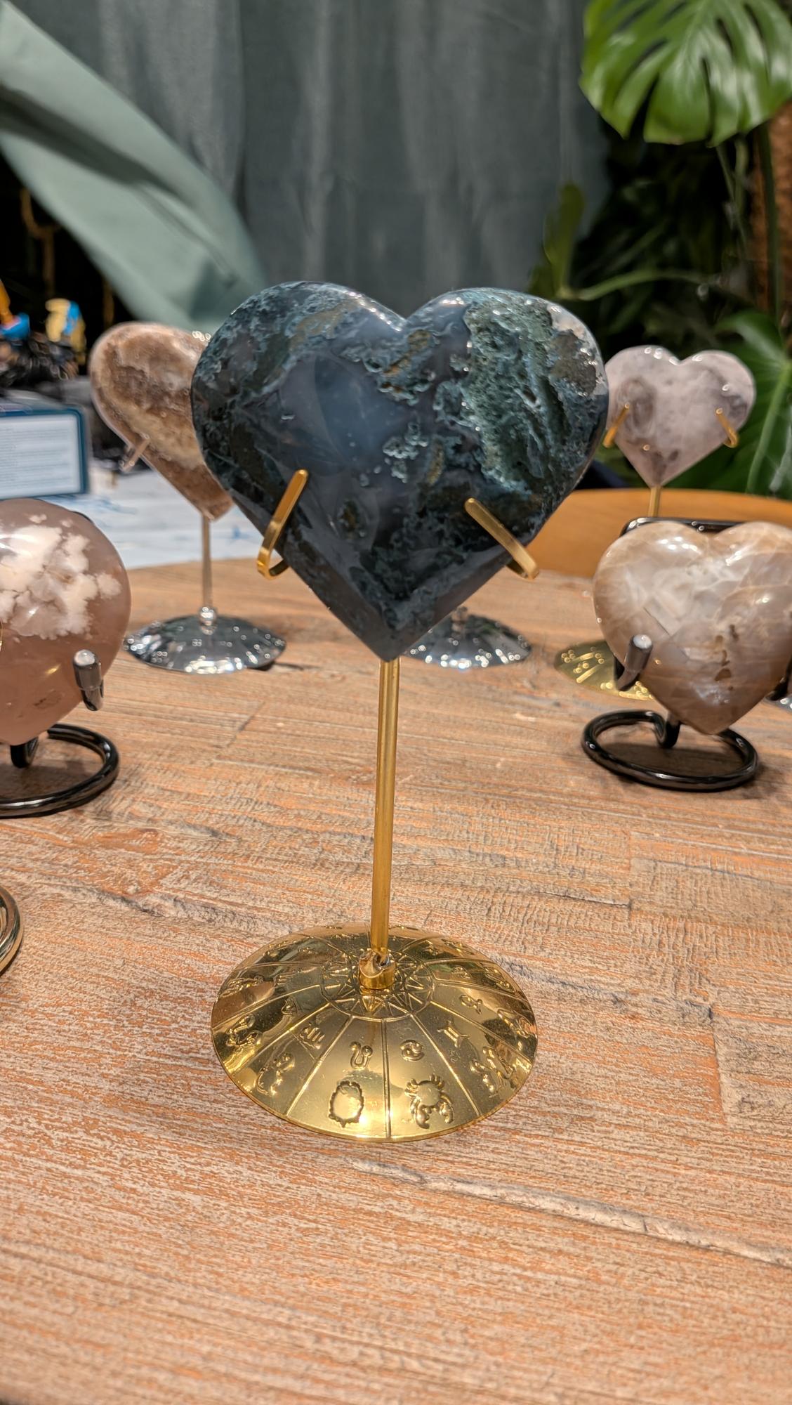 "Diepgroen mosagaat hart met natuurlijke patronen op een goudkleurige standaard met dierenriemtekens."