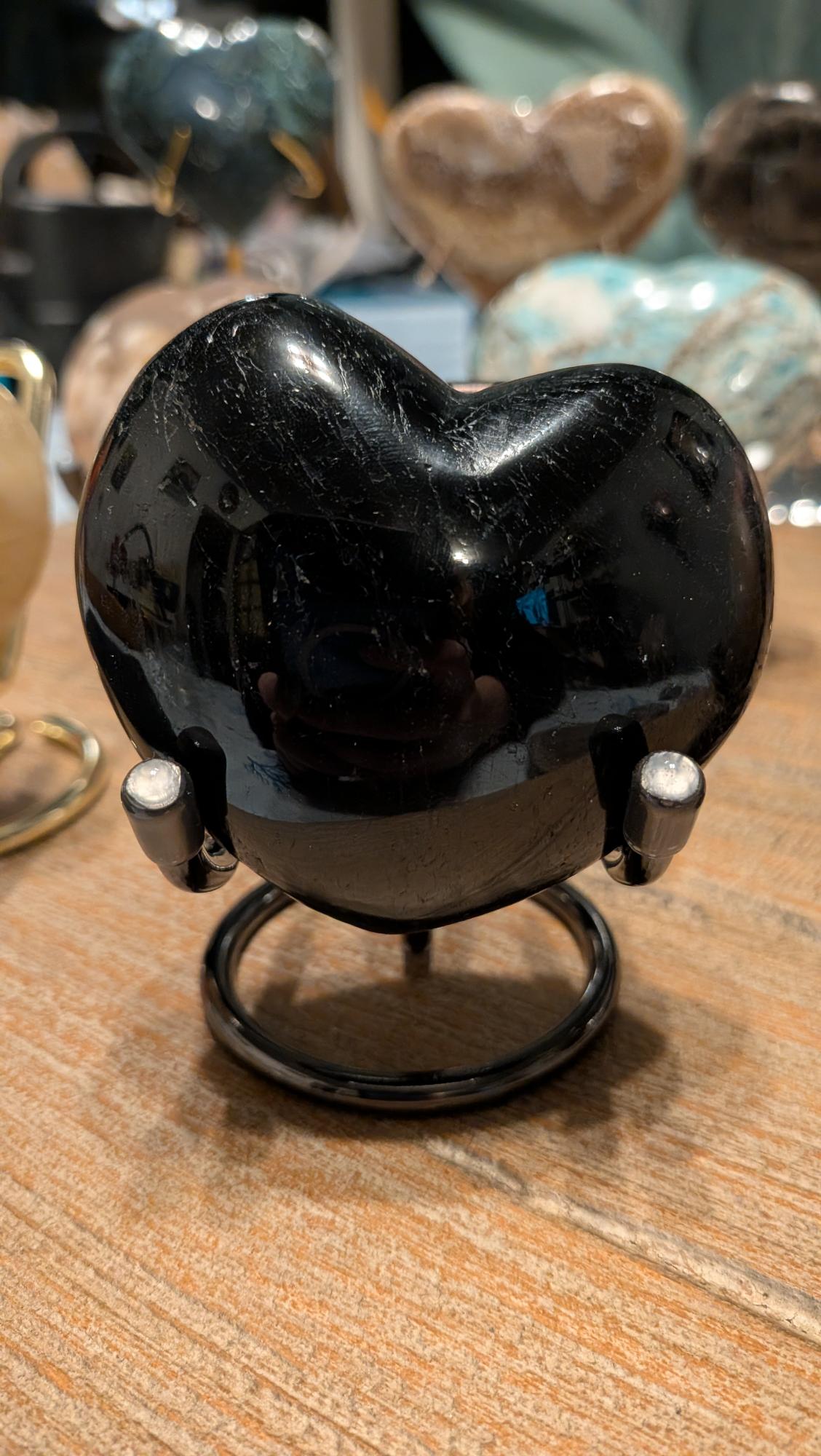 "Hoogglans gepolijst Zwarte Onyx hart van 289 gram op een zilverkleurige standaard."