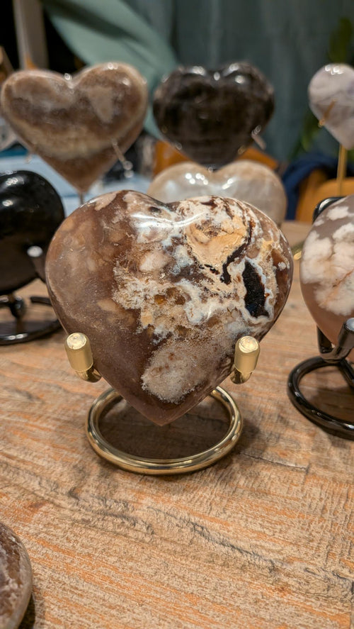 "Handgeslepen hart van natuurlijke Bloemagaat (Flower Agate) uit Madagaskar, gepresenteerd op een gouden metalen standaard."