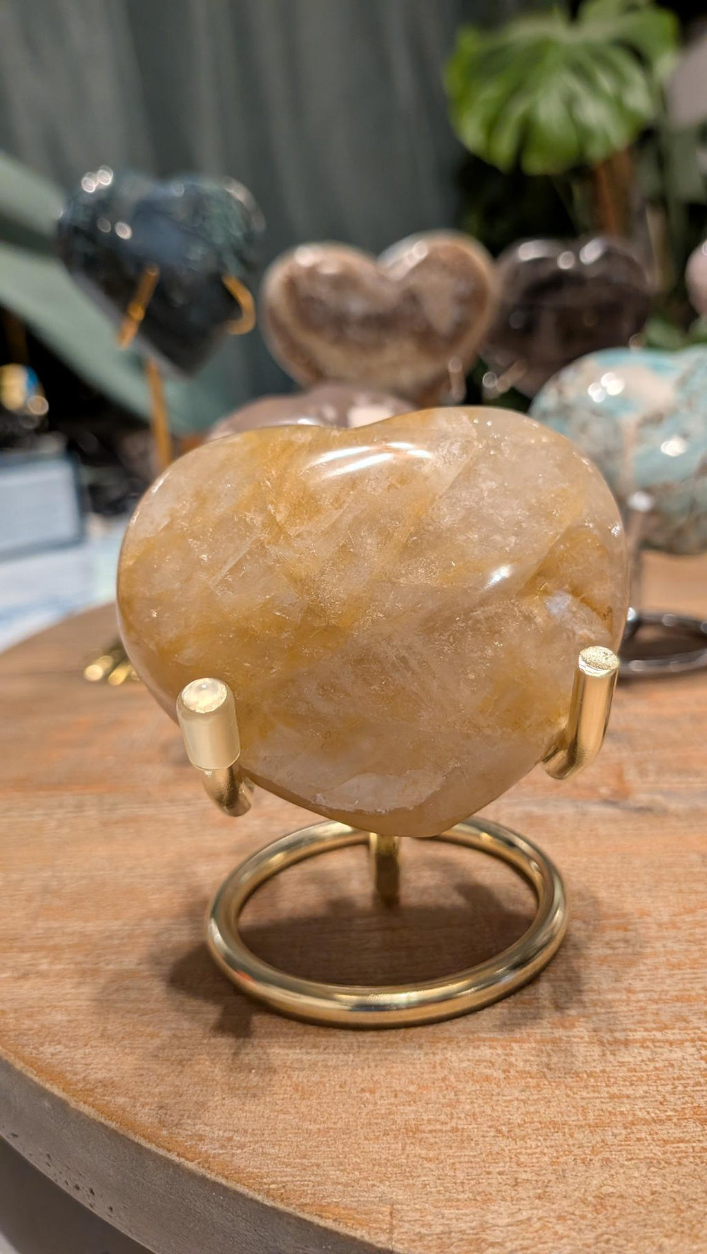 "Handgeslepen Golden Healer hart van 187 gram op een goudkleurige standaard, met een heldere gele gloed."