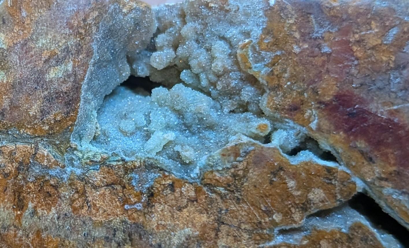 Detailopname van een brede kristalholte (druzy) in de Oceaan Jaspis maan, tonend de fonkelende kristalstructuur.