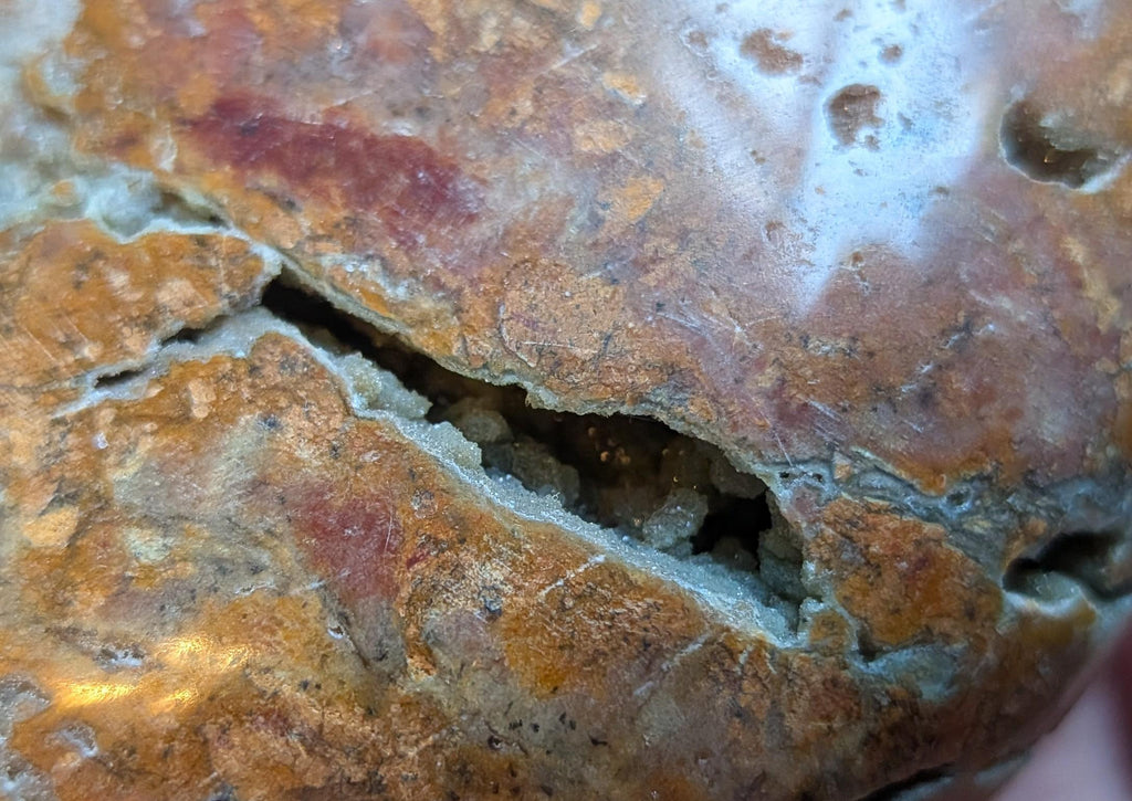 Macrofoto van de textuur en kleurgradaties van de Oceaan Jaspis met kleine druzy openingen.