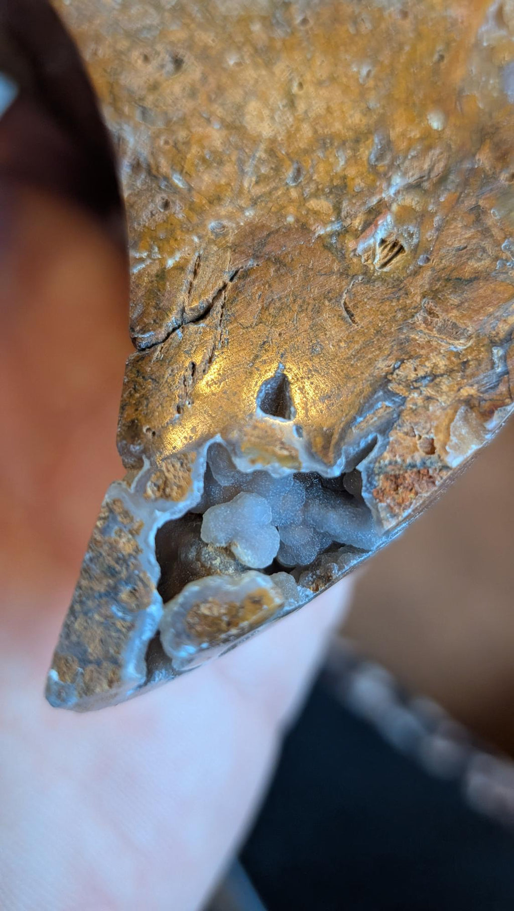 Detailopname van een natuurlijke holte in de Oceaan Jaspis maan waarin witte en lichtblauwe kristallen (druzy) zichtbaar zijn.