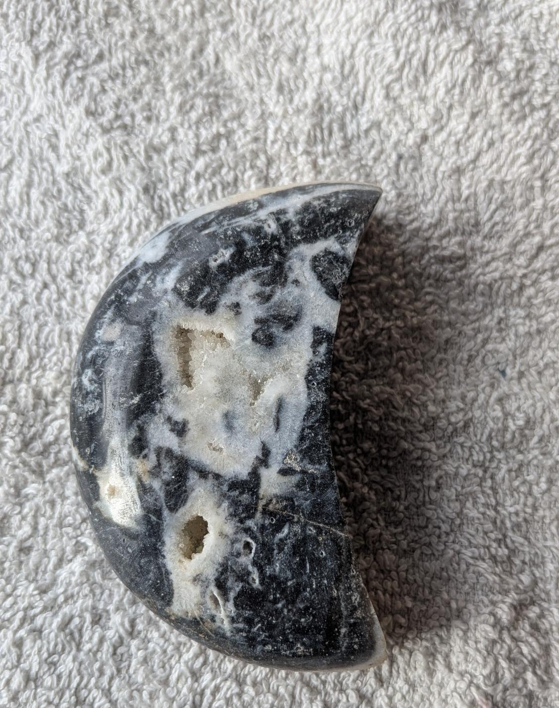 Handgeslepen Orka Agaat in de vorm van een halve maan, 206 gram, met witte en grijze oceaan-patronen en een grote fonkelende kristalholte (druzy) in het midden.