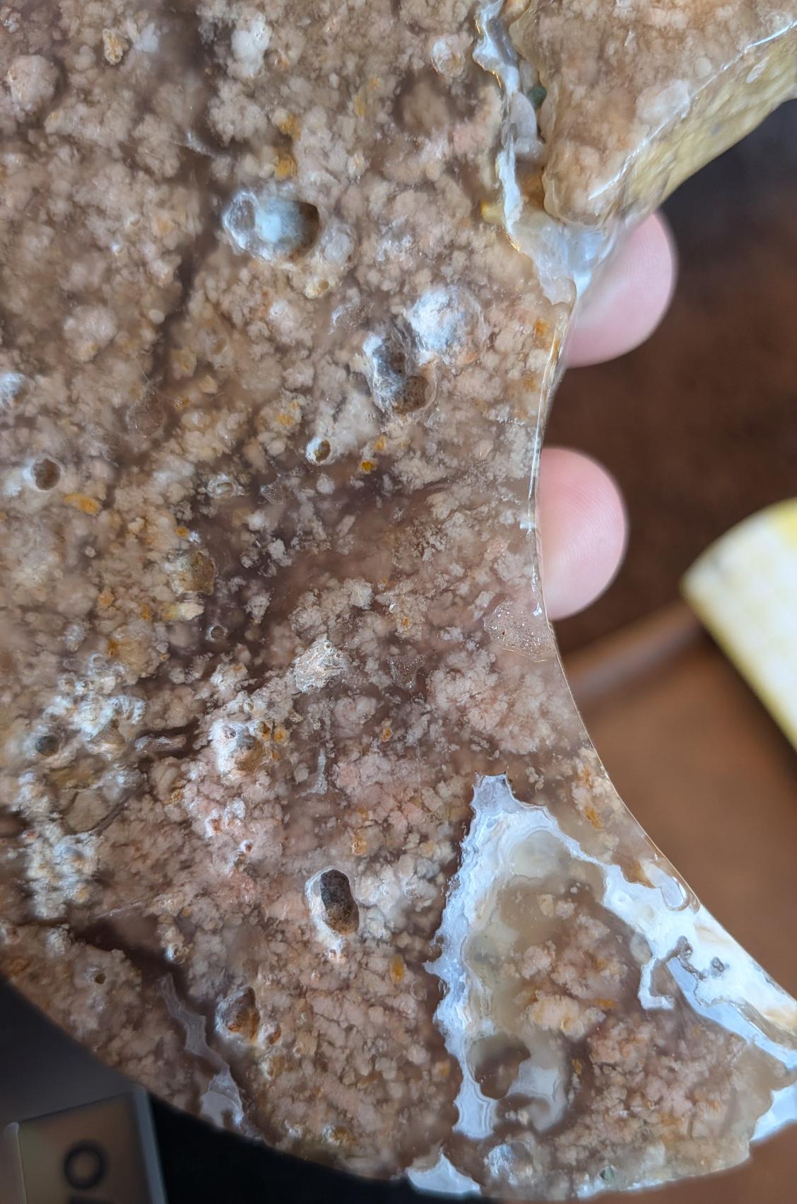 Close-up van de onderzijde van de Bloesem Agaat maan, met de focus op een fonkelende kristal-druzy opening en de gelaagde opbouw van de steen in verschillende tinten roze en wit.