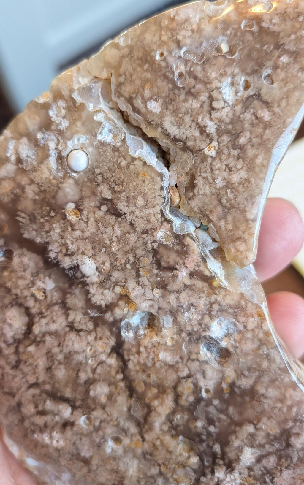 Gedetailleerde macro-opname van het oppervlak van de Bloesem Agaat, waarbij de unieke 3D-bloemstructuren, kleine natuurlijke kristalholtes en de zachte overgang tussen transparante en ondoorzichtige lagen zichtbaar zijn.