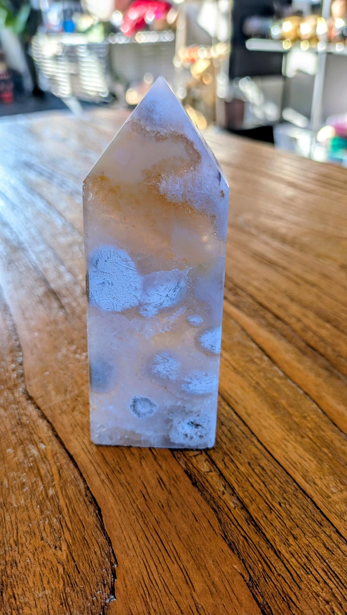 "Gepolijste bloem agaat toren van 11 cm hoog met zachte roze patronen en een kleine glinsteredne kristalholte aan de bovenzijde."