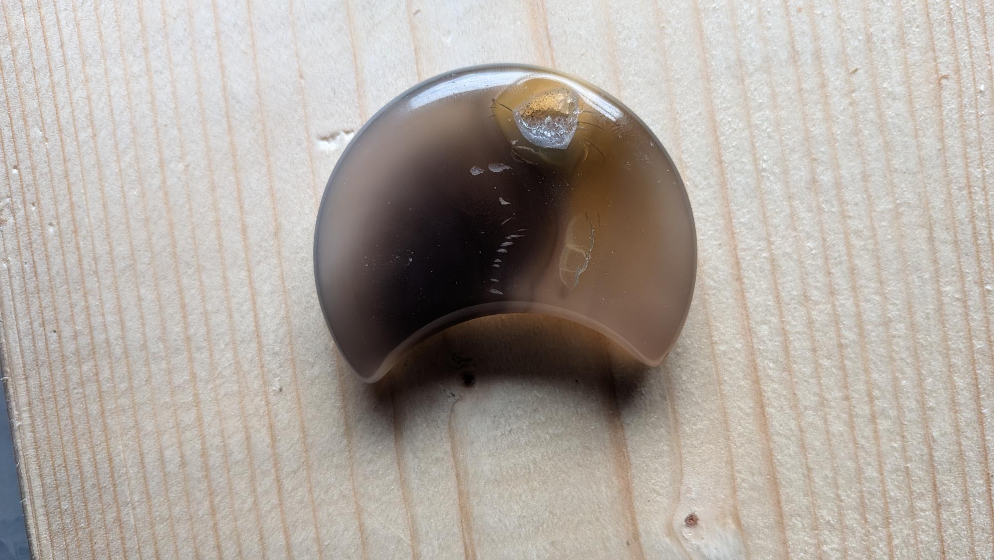 Handgeslepen rookgrijze Agaat edelsteen in maanvorm met een opvallende kristalgeode aan de bovenkant, 5 centimeter groot.