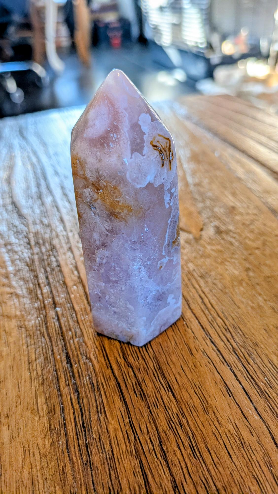 "Detail van de bloemvormige insluitingen in een roze amethist bloem agaat toren op een houten ondergrond."