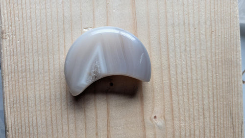 Handgeslepen grijze Agaat edelsteen in maanvorm met strakke geometrische kleurbanden en een klein kristal-accent, 5,5 centimeter groot.