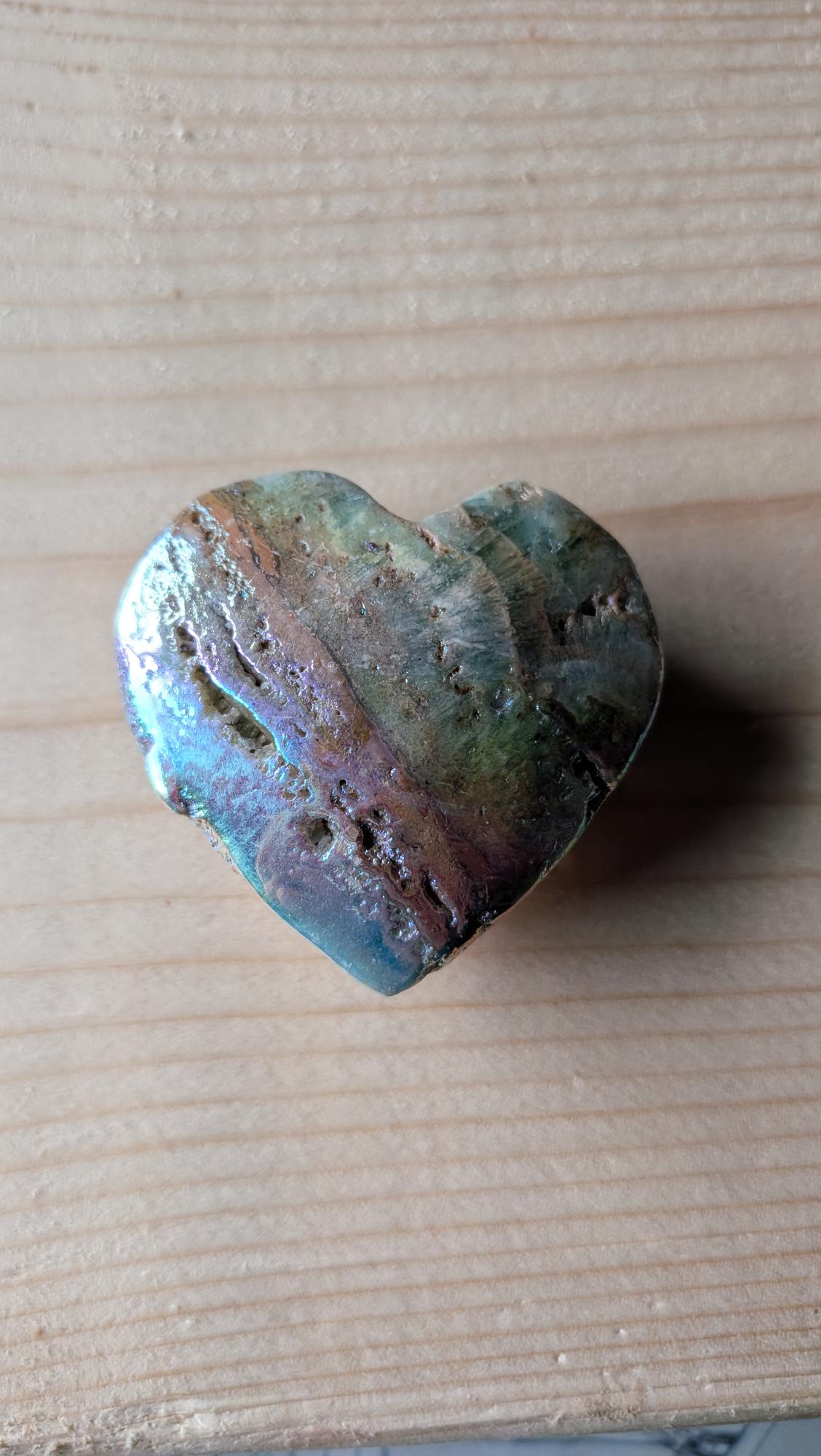 Een dik, glanzend hart van Aura Sphaleriet met een iriserende goud-paarse glans, 5 cm groot, gefotografeerd op een houten ondergrond.