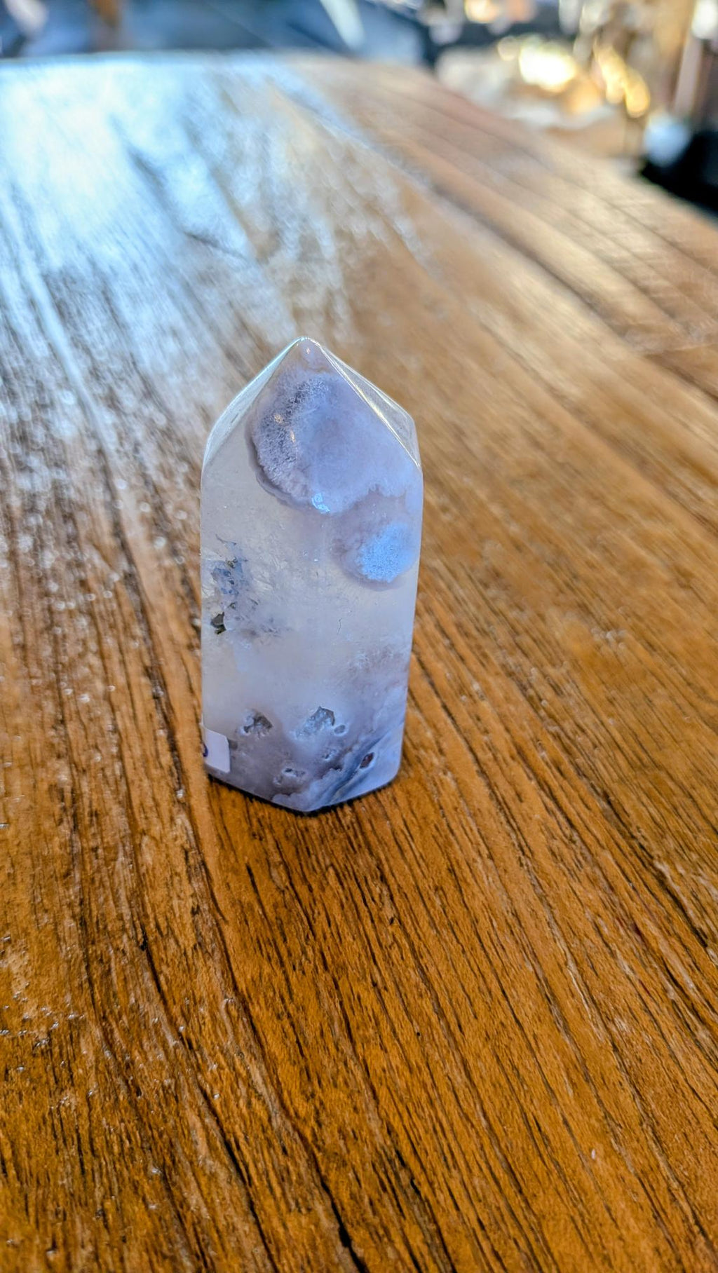 "Achterzijde van een 73 gram bloem agaat toren met zachte pastelkleurige patronen op een houten achtergrond."