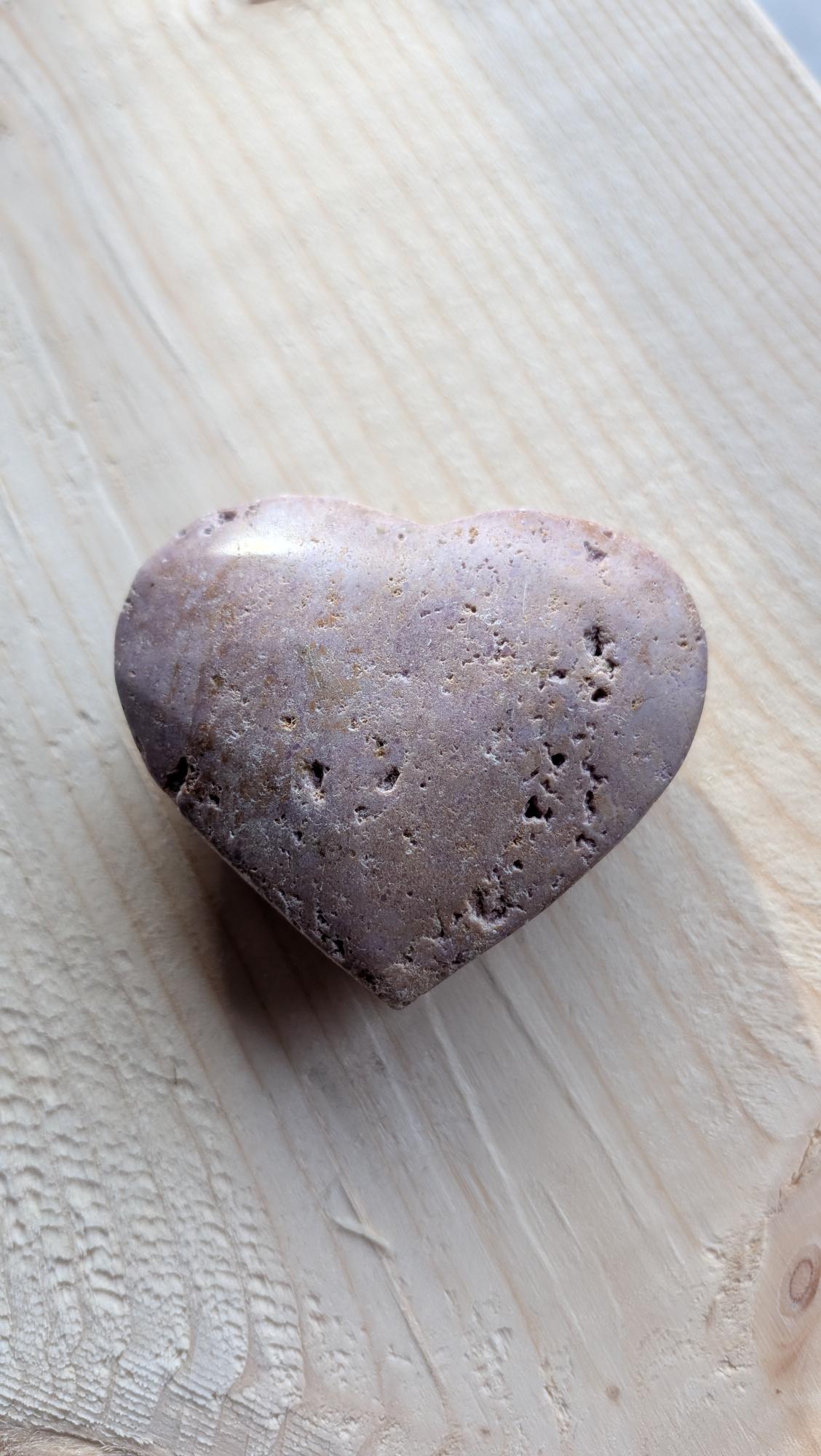 Handgeslepen hartje van lila Phosphosideriet edelsteen met natuurlijke gele insluitingen, 5,5 cm breed op een houten ondergrond.