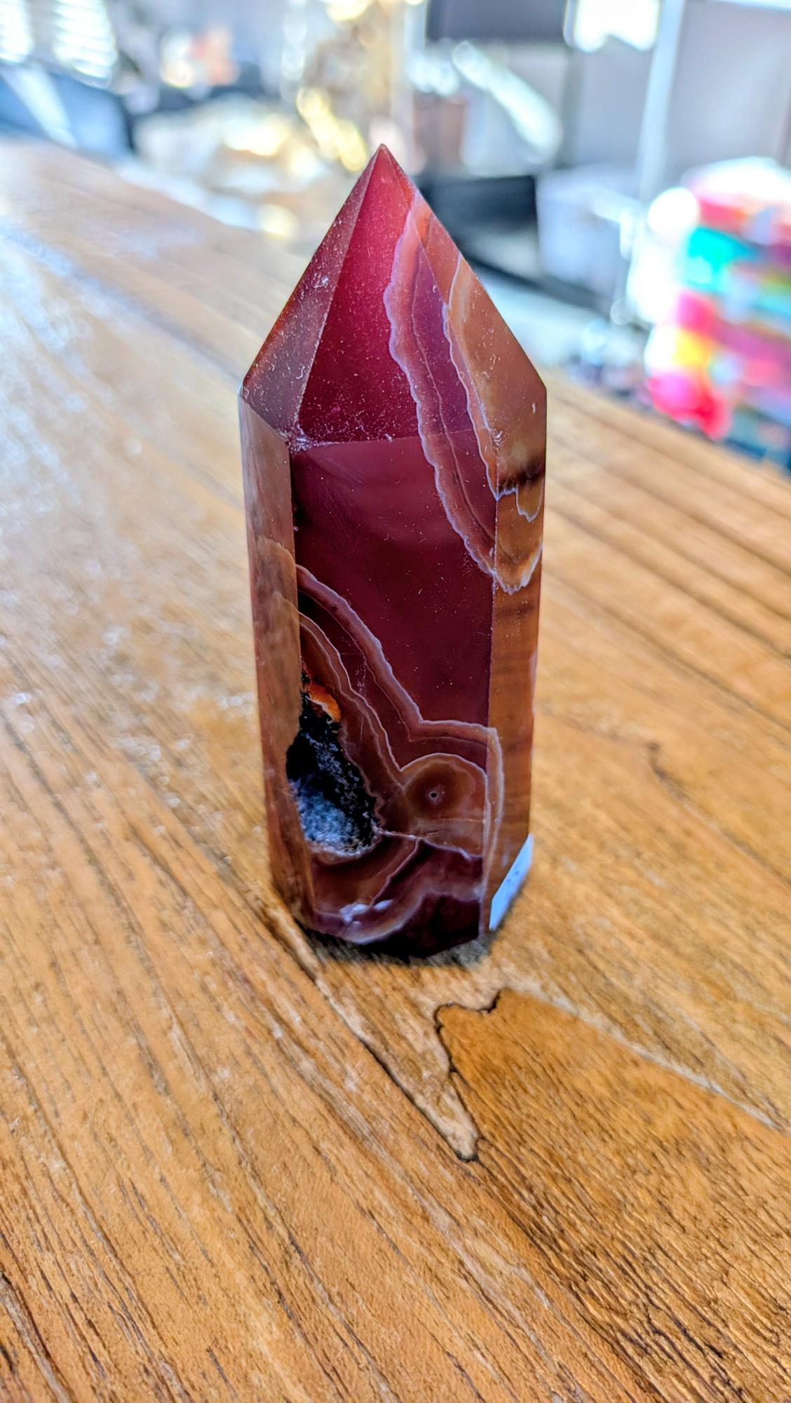 "Zijaanzicht van een dieprode carneool toren met unieke ronde oog-patronen en een kleine natuurlijke opening."