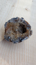 Natuurlijke agaat geode met goudbruine rookkwarts kristallen op een houten achtergrond.