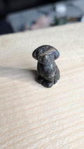 Handgesneden miniatuur hondje van donkerblauwe sodaliet edelsteen op een houten ondergrond.