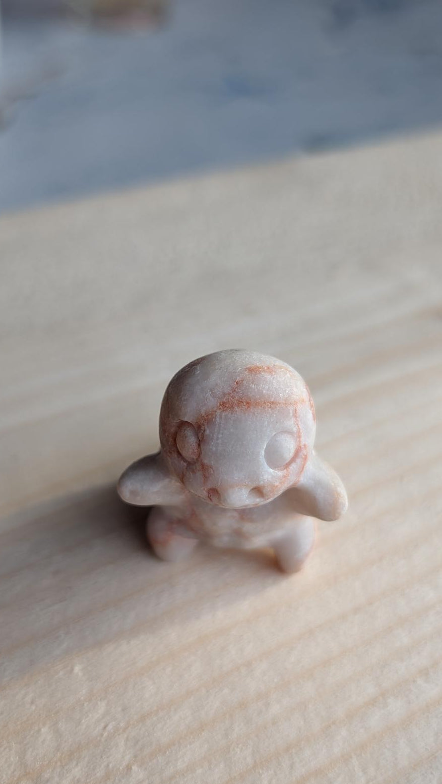 Handgesneden Squirtle Pokémon van zandkleurige landschapsjaspis op een houten achtergrond.