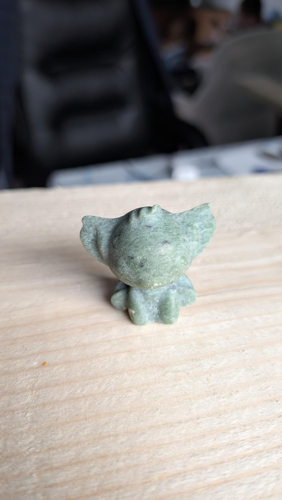 Handgesneden Stitch figuurtje van groene aventurijn edelsteen op een lichte houten achtergrond.