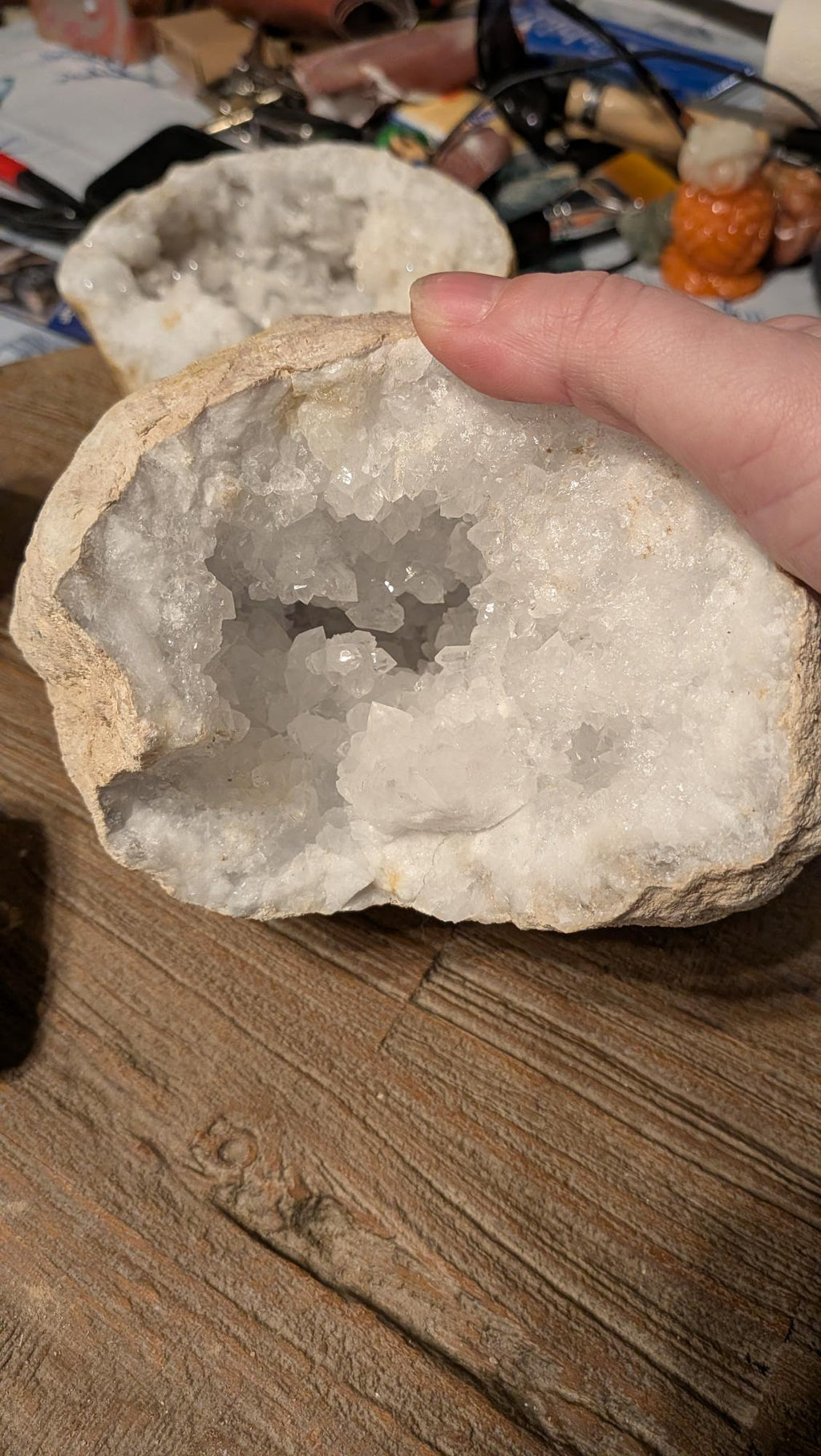 Grote massieve kristalgeode van 2,7 kilo met een diepe binnenzijde vol glinsterende witte kristallen, getoond op een houten achtergrond.