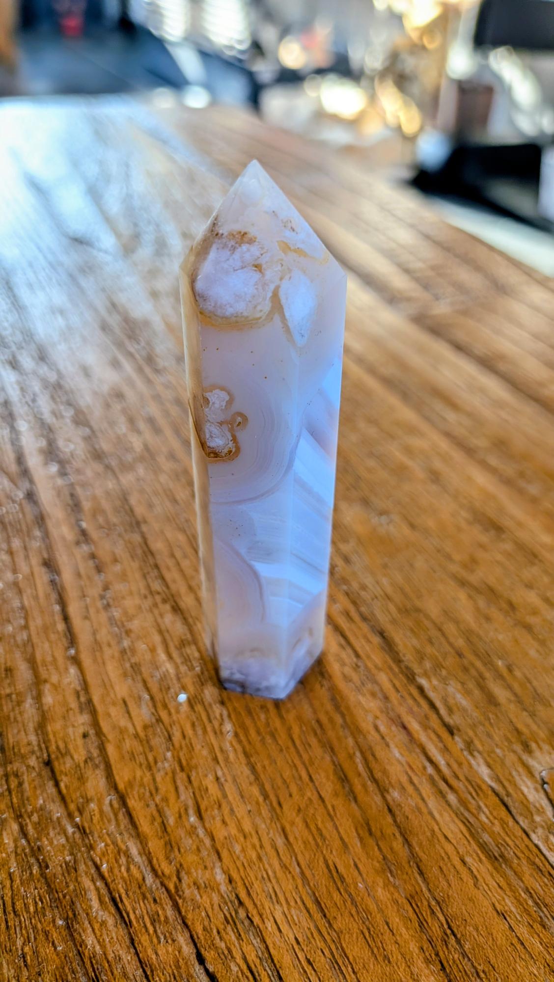 Gepolijste Bloem Agaat toren met zachte roze tinten en witte bloemvormige chalcedoon patronen op een houten ondergrond.