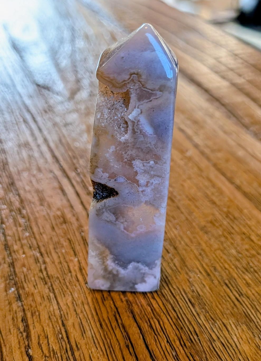 Verticale Bloem Agaat kristal toren van 8 cm hoog met witte bloesemachtige patronen op een houten ondergrond.