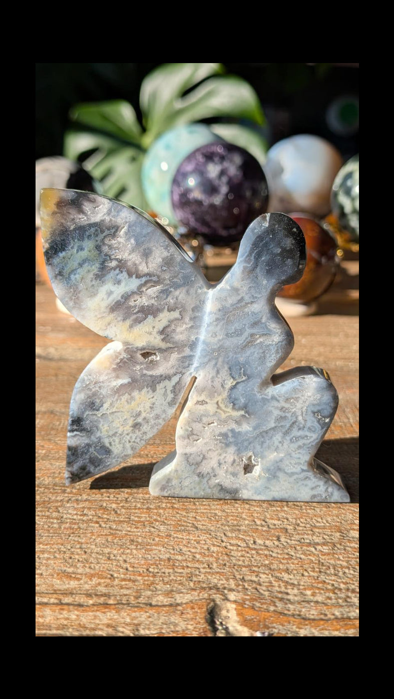 Handgesneden elfje van Blue Pacific Agaat met brede vleugels en natuurlijke kristalholtes, 8 cm breed vakmanschap uit Java.