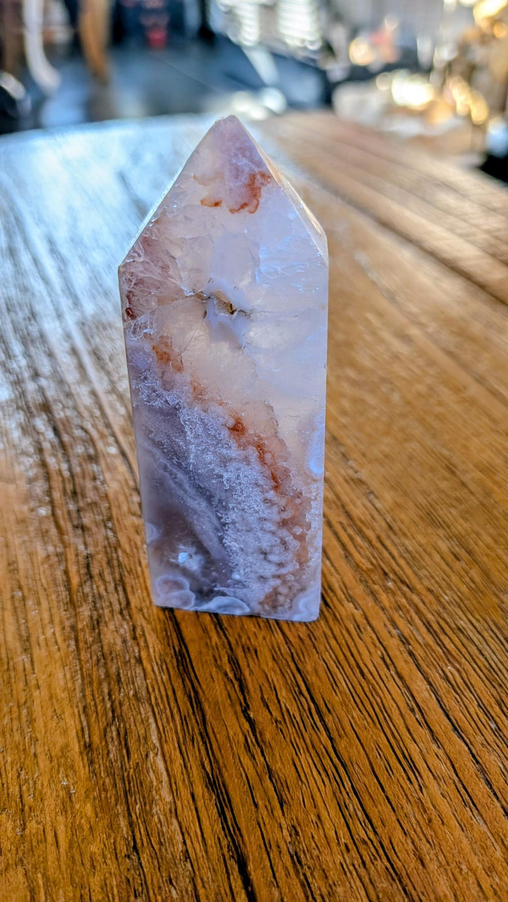 Verticale Bloem Agaat kristal toren van 8,5 cm met witte chalcedoon bloemen en rode kleuraccenten op een houten achtergrond.