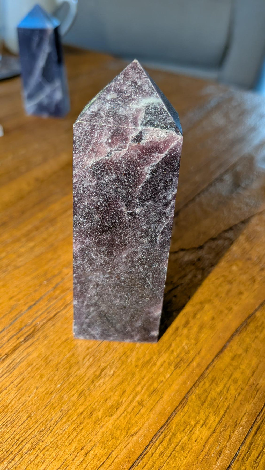 Paarse Lepidoliet kristal toren van 9 cm met natuurlijke glinsteringen op een houten ondergrond.