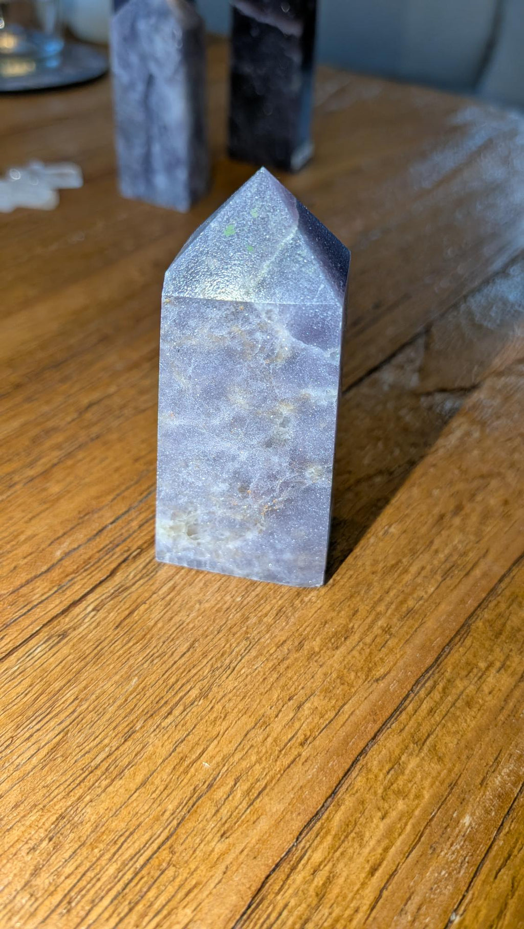 Verticale lila-paarse Lepidoliet kristal toren van 7 cm hoog met zilveren glinsteringen op een houten achtergrond.