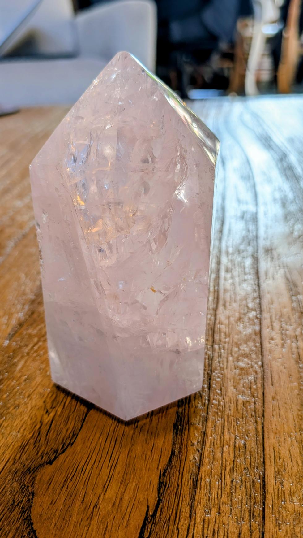 Grote, robuuste Rozenkwarts kristal toren van 10,5 cm hoog met een gewicht van 524 gram op een houten ondergrond.