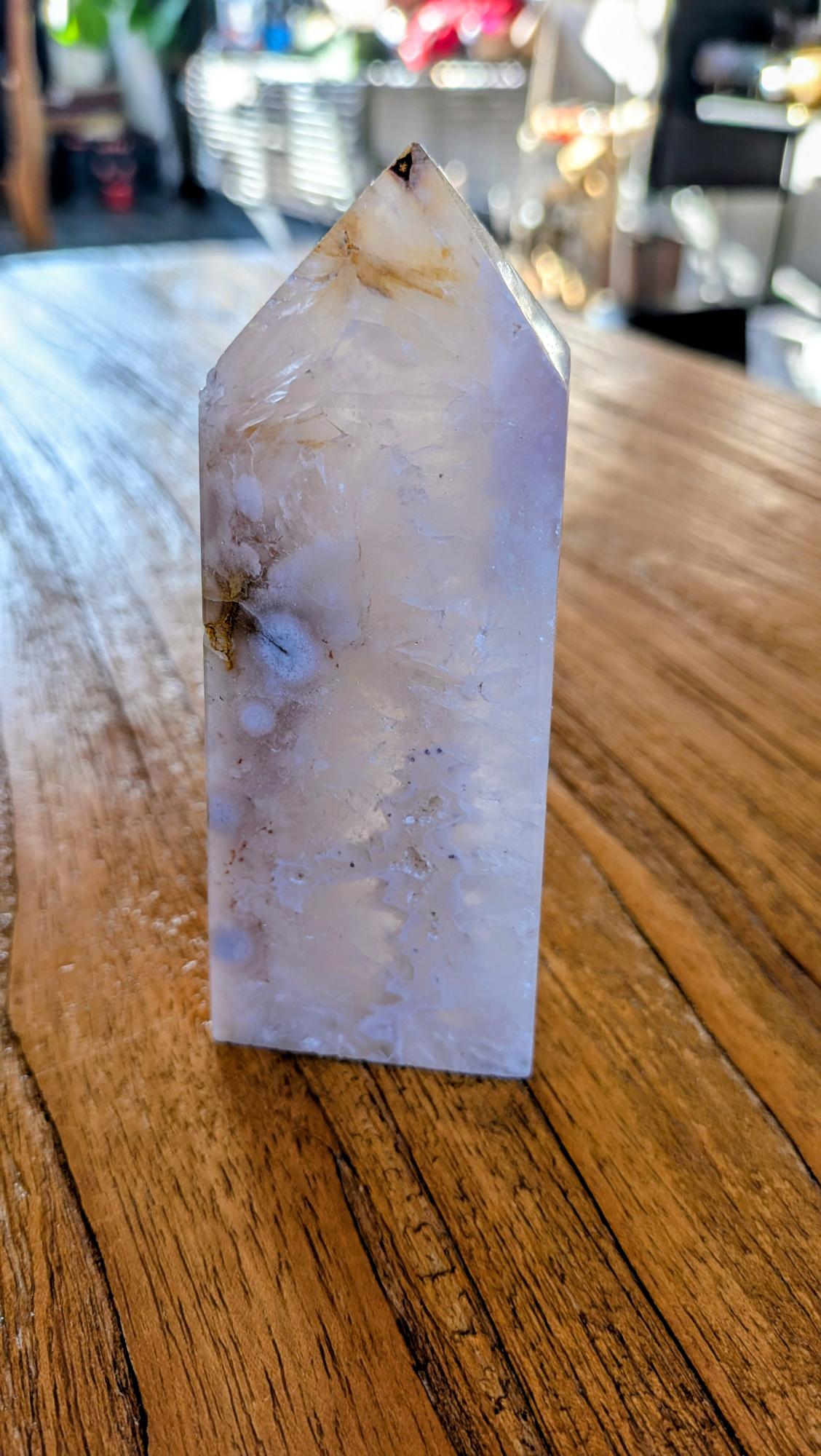 "Gepolijste Bloemagaat toren met witte bloemachtige patronen in een lichtroze en witte kristalstructuur, staand op een houten ondergrond."