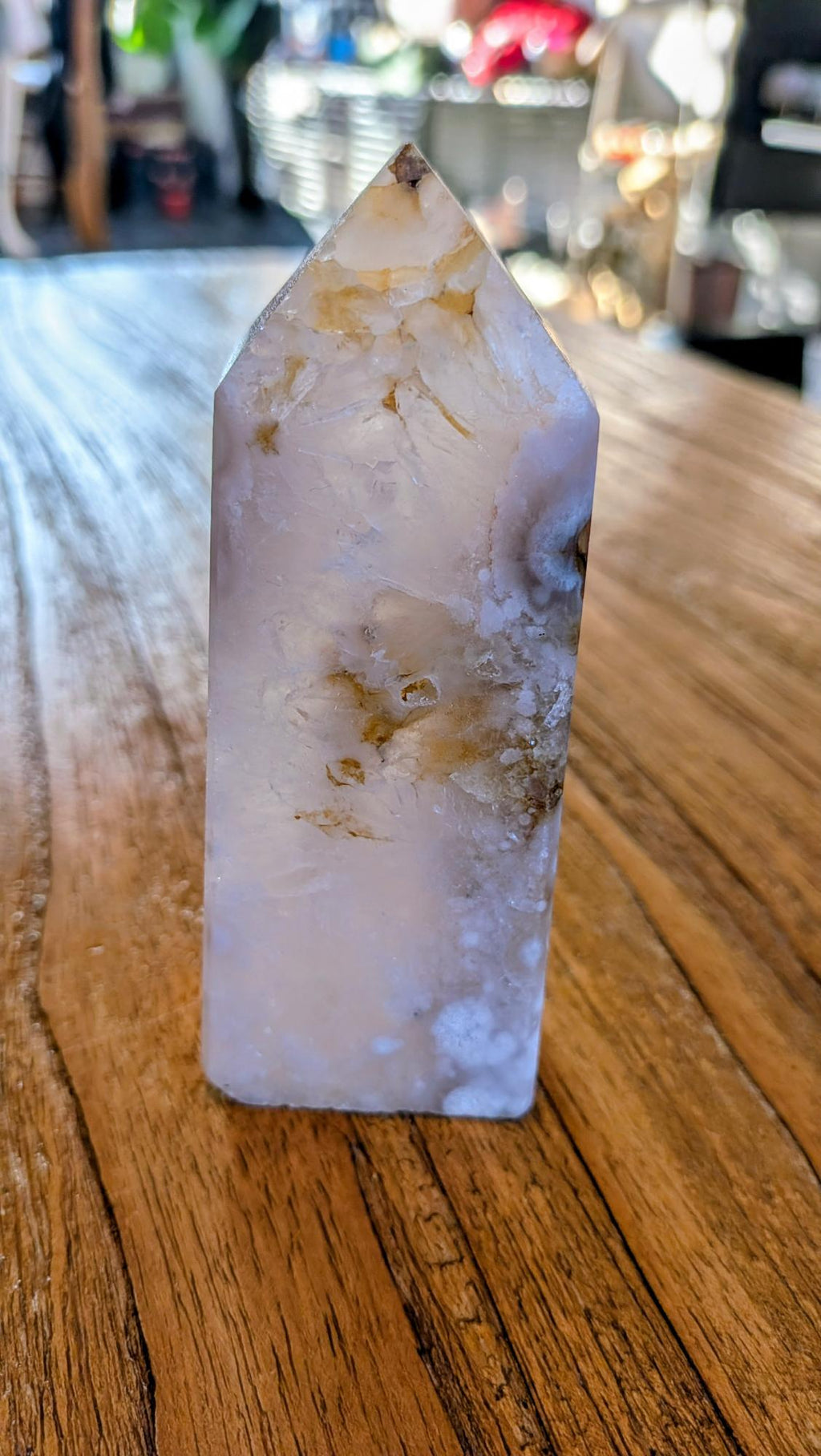 "Gepolijste Bloemagaat toren met witte bloemachtige patronen in een lichtroze en witte kristalstructuur, staand op een houten ondergrond."