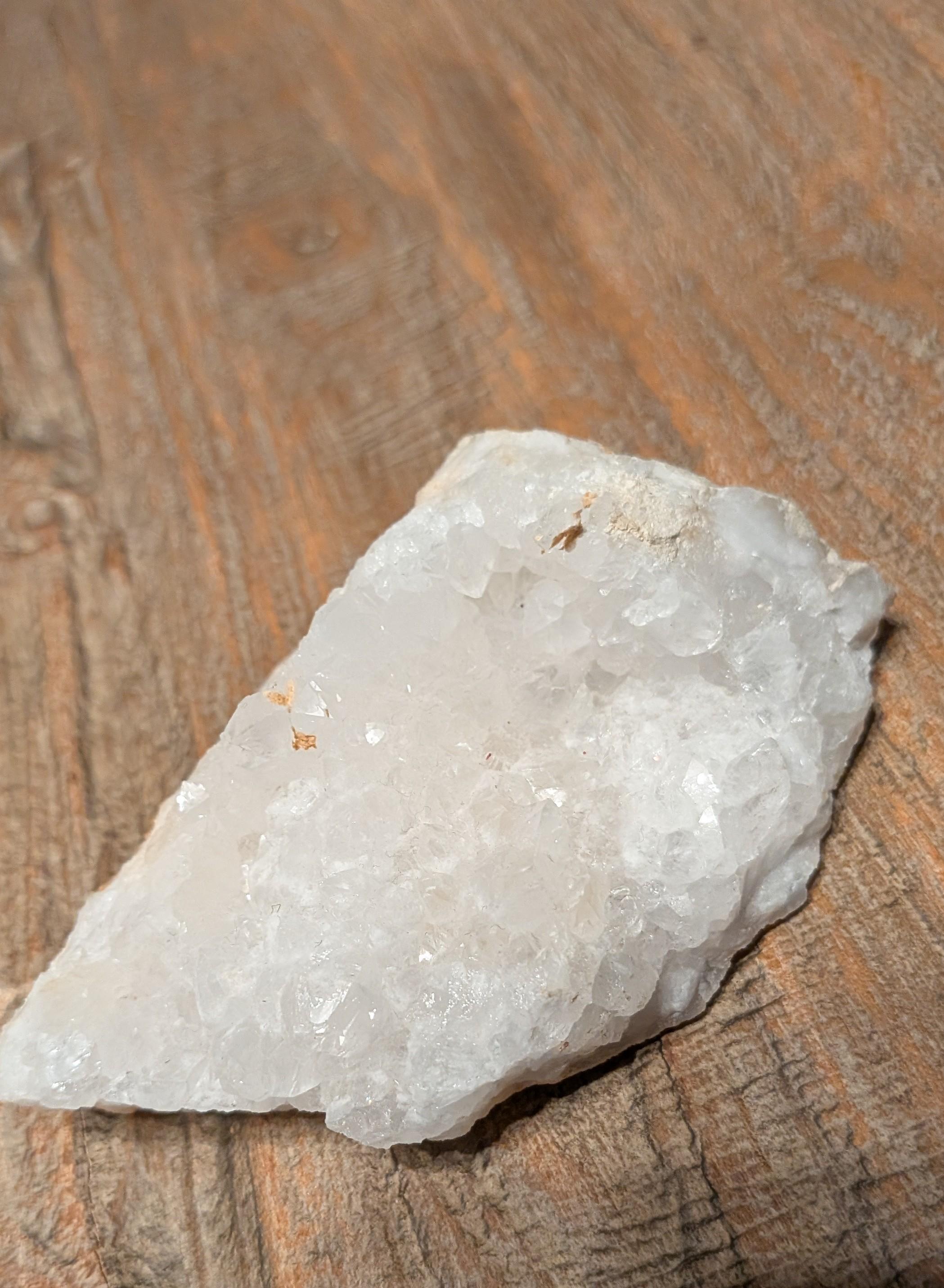 Helder wit Bergkristal cluster van 212 gram met scherpe kristalpunten op een houten ondergrond.