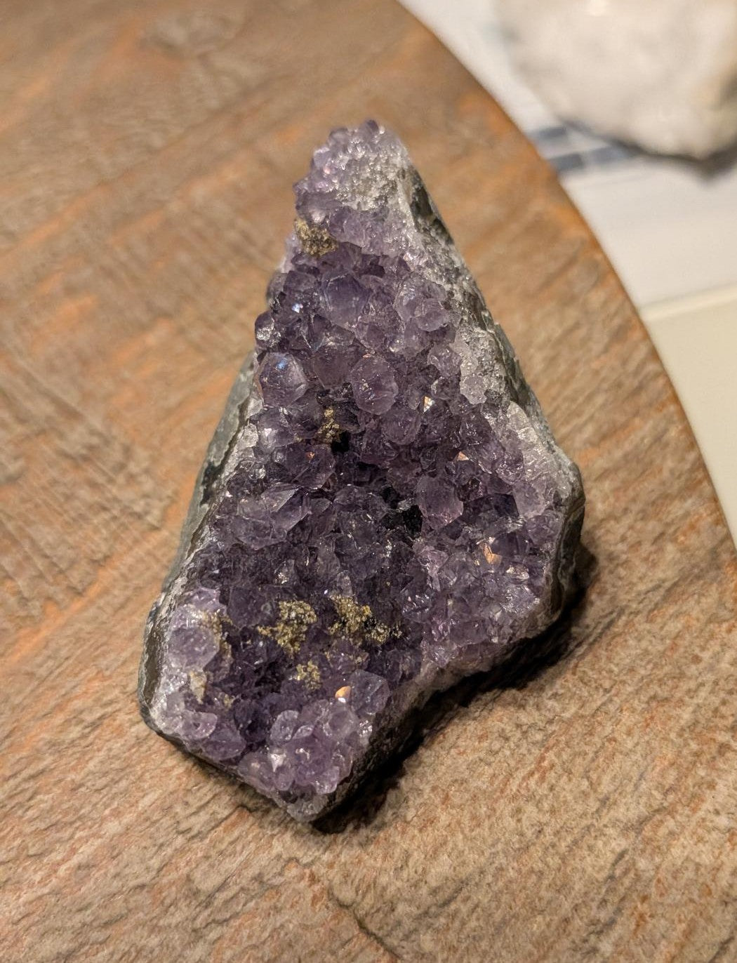 Handzaam paars Amethist cluster van 67 gram met schitterende kristalpunten op een houten ondergrond.