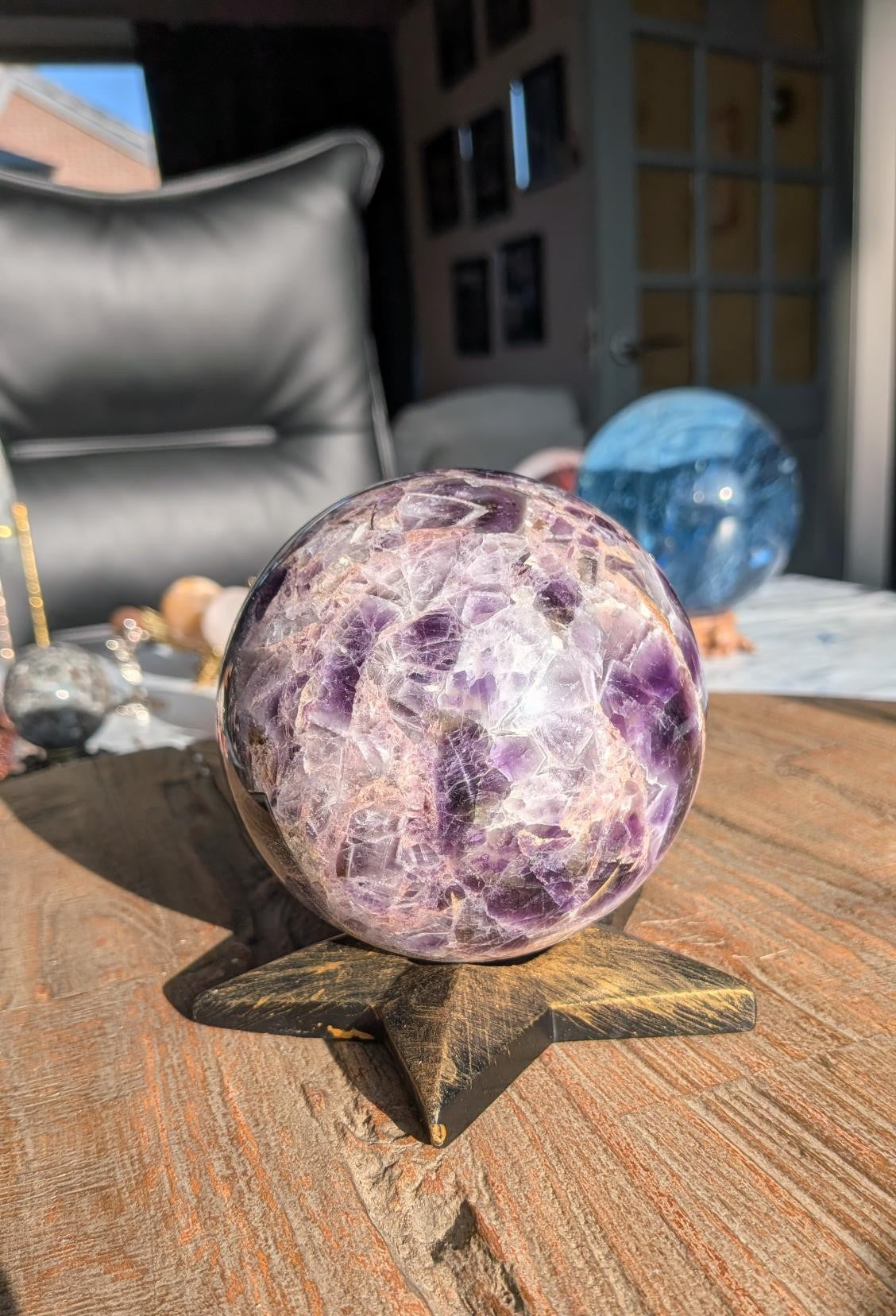 Grote paarse AAA Chevron Amethist bol van 10 cm diameter en 1240 gram met witte V-patronen op een zwarte ster-standaard