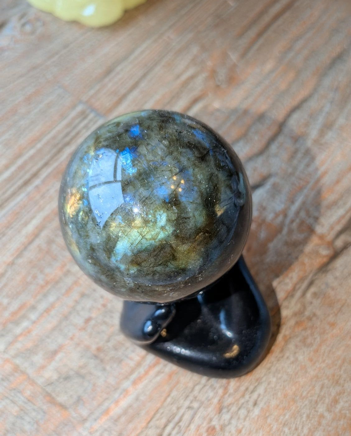 Close-up van de Labradoriet bol die sterke goudkleurige en blauwe flitsen (labradorescentie) toont onder direct licht.