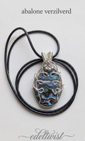 Handgemaakte ovale abalone schelp hanger met een iriserend kleurenspel van blauw, groen en paars, vakkundig gewrapt in sierlijk verzilverd draad met kraaldetails door Edeltwist op een neutrale achtergrond.