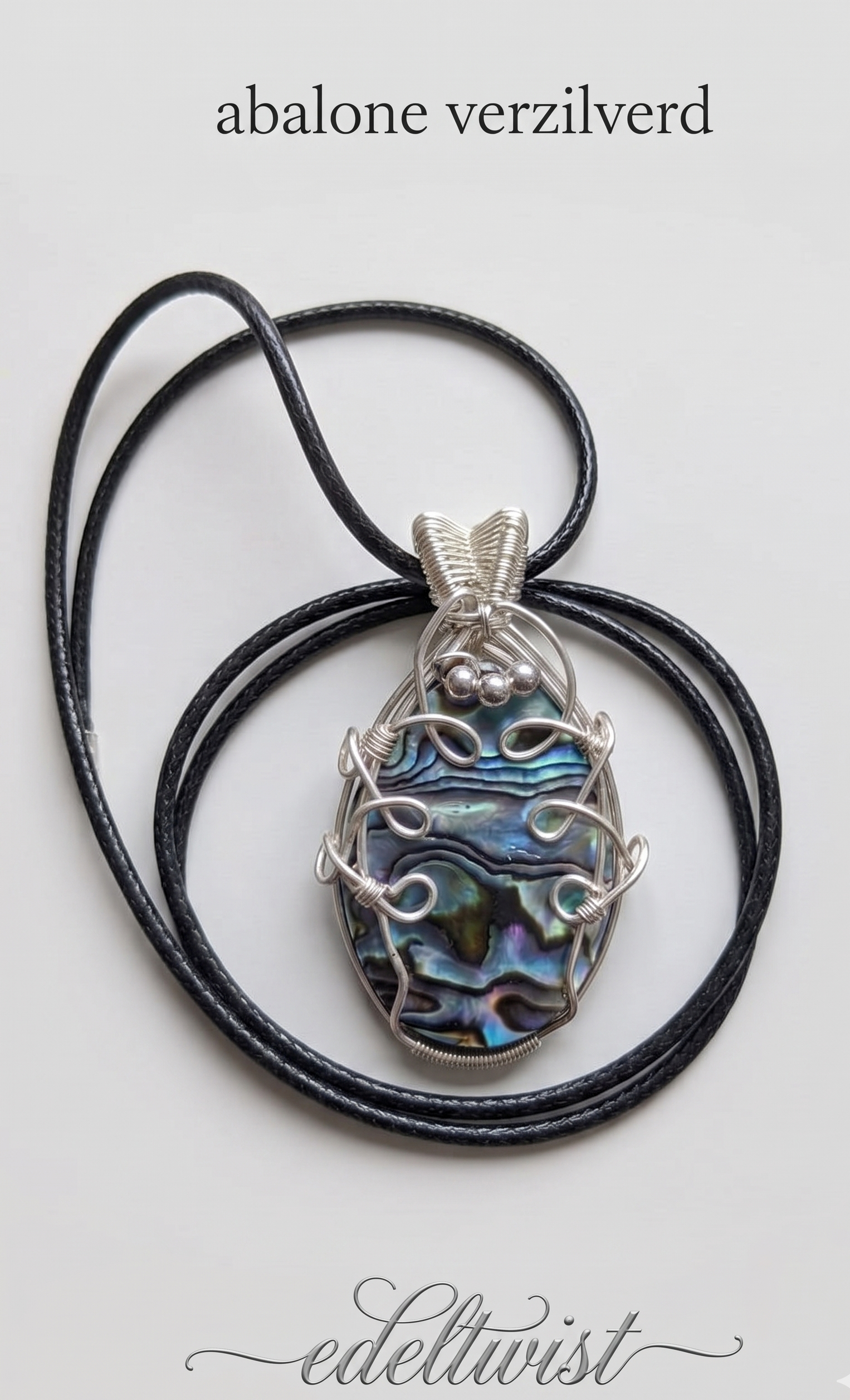 Handgemaakte ovale abalone schelp hanger met een iriserend kleurenspel van blauw, groen en paars, vakkundig gewrapt in sierlijk verzilverd draad met kraaldetails door Edeltwist op een neutrale achtergrond.