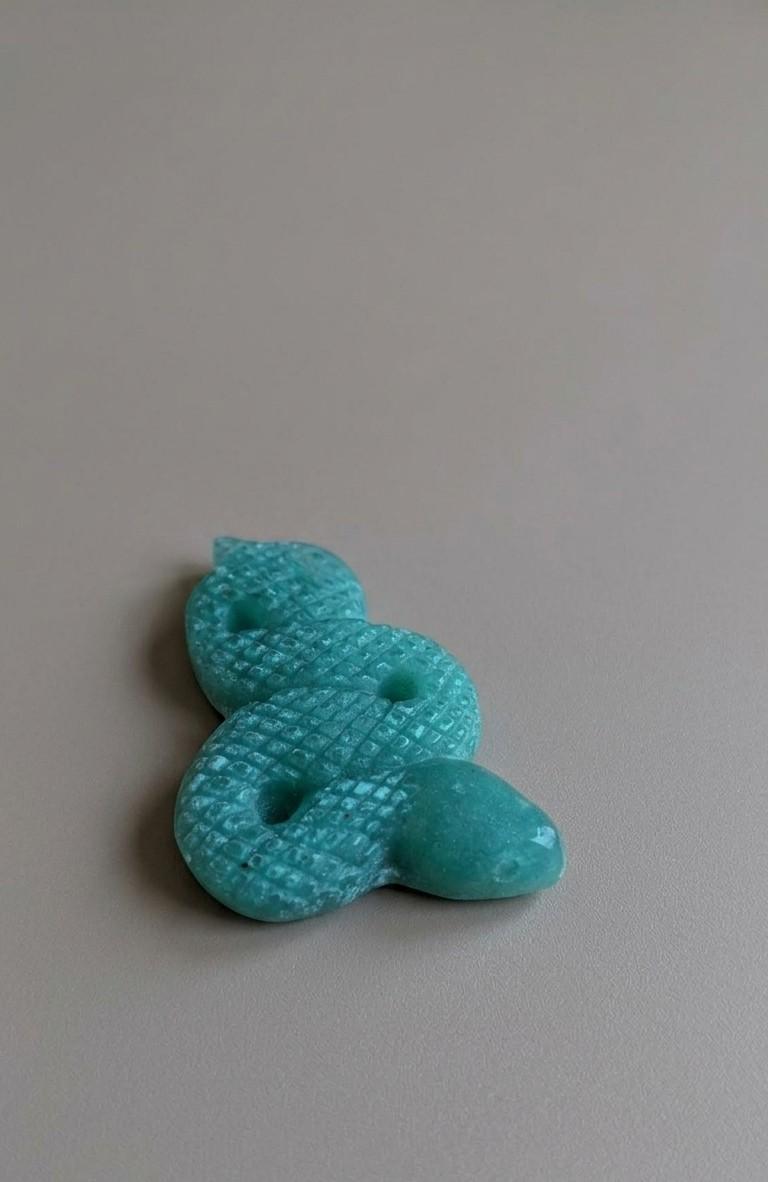 Gedetailleerd edelsteen figuurtje van een gekronkelde slang met schubbenpatroon, geslepen uit helder blauwgroene amazoniet.