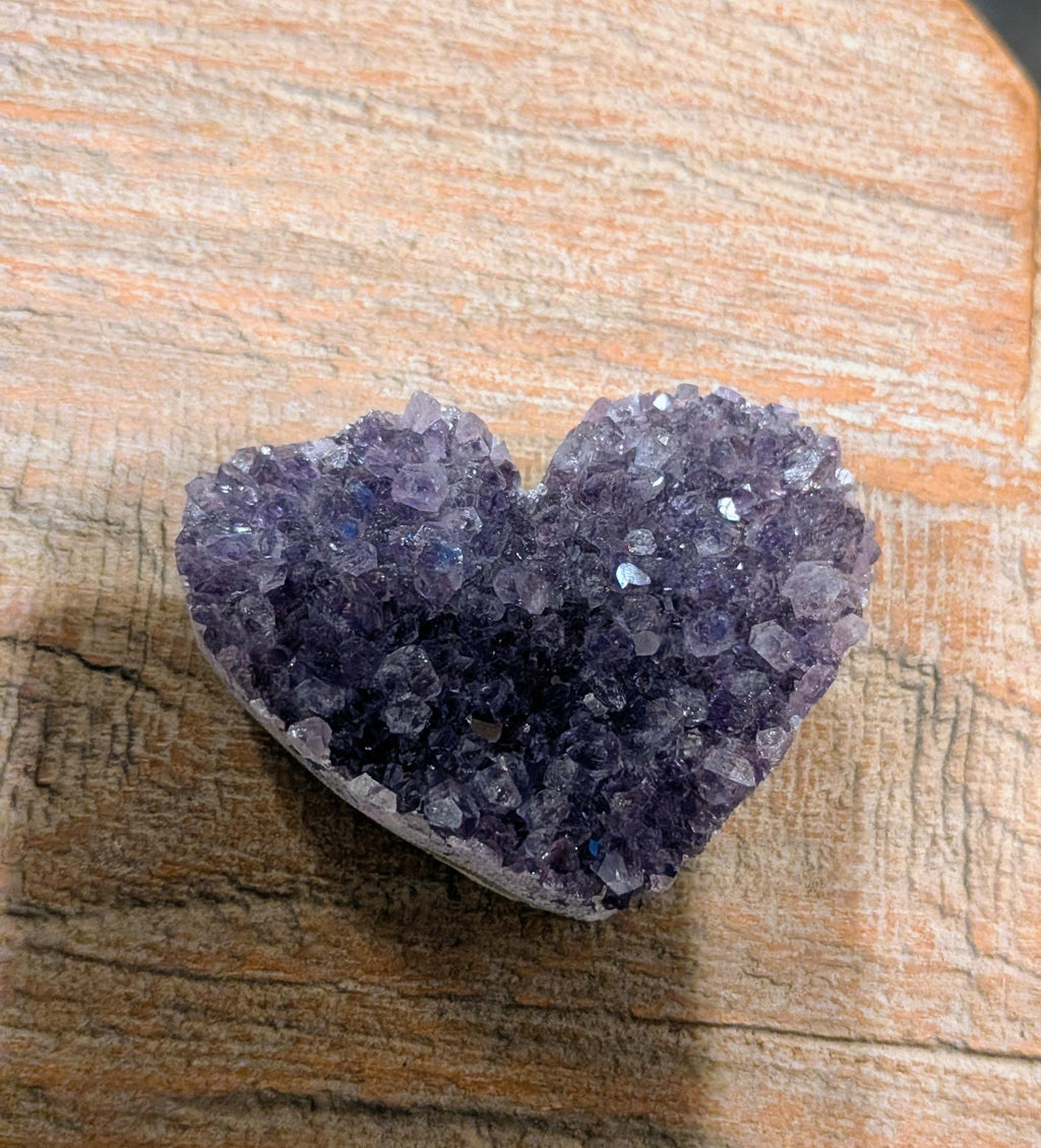 "Een compact Amethist Geode hart in de palm van een hand om het formaat van 48 gram te tonen."