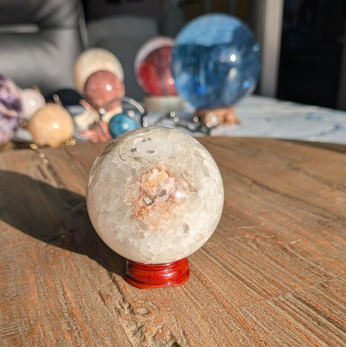 Vooraanzicht van een 6 cm Roze Amethist bol met witte bloemagaat patronen op een kleine houten standaard.