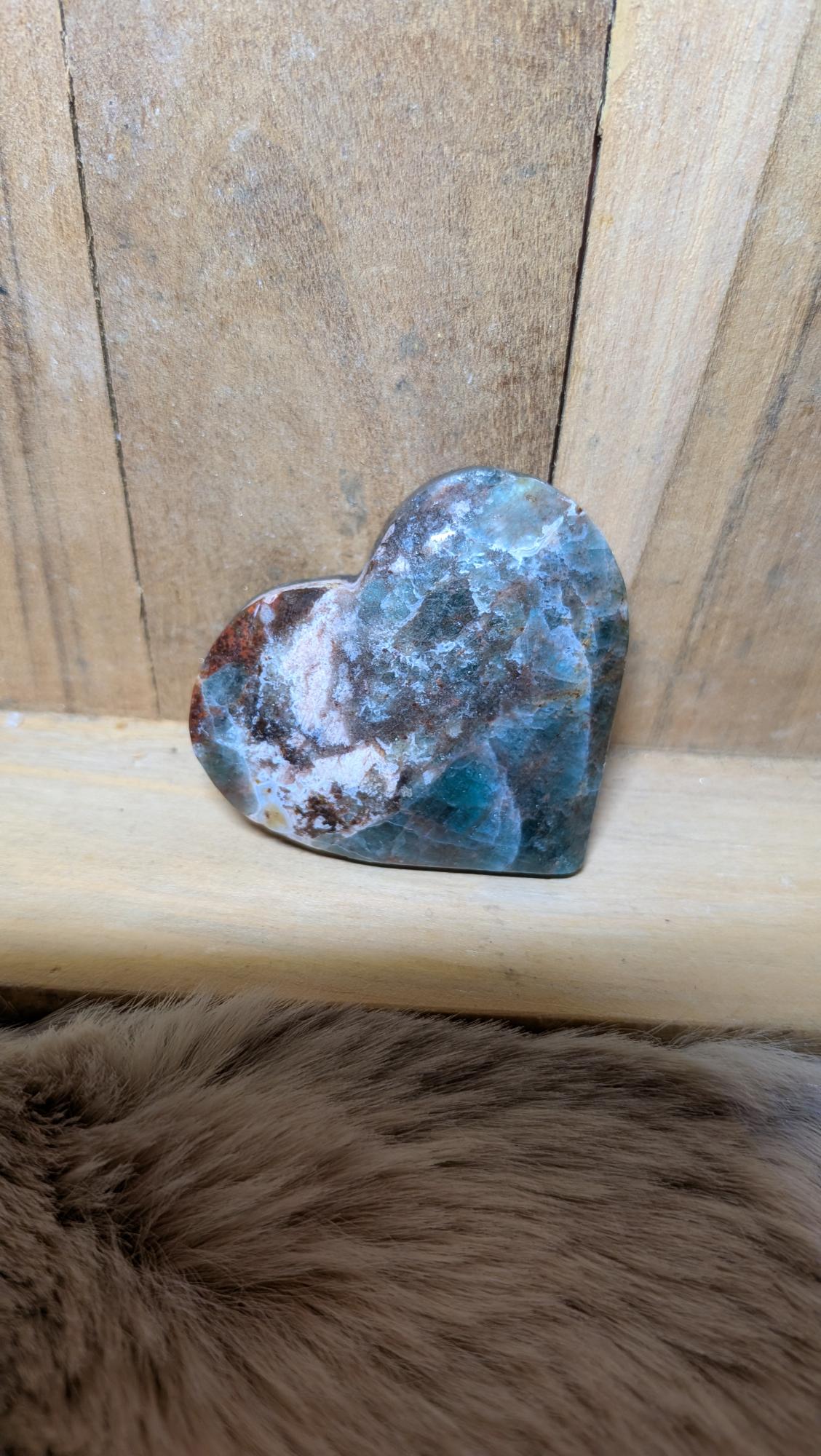 Middelmaat edelsteen hart van apatiet met blauwe en roodbruine tinten op een houten achtergrond