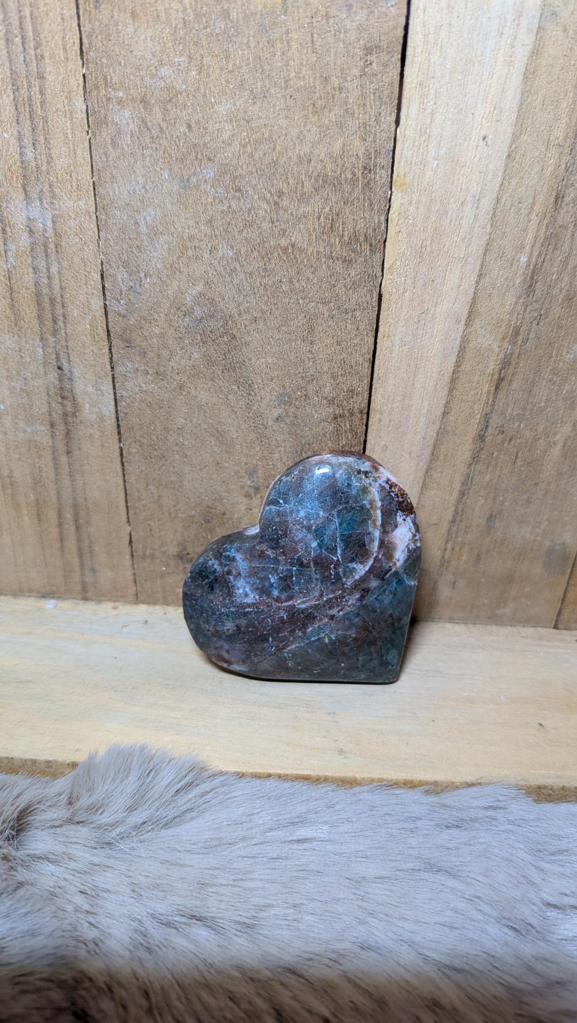 Middelmaat edelsteen hart van apatiet met blauwe en roodbruine tinten op een houten achtergrond