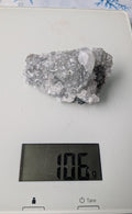 Een helder Apofylliet cluster van 106 gram met geometrische, glasachtige kristallen, gefotografeerd op een digitale weegschaal.