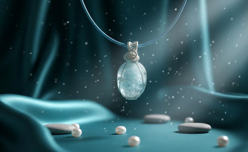 Handgemaakte verzilverde wire-wrap hanger met een facet edelsteen en een klein kristal, zwevend tegen een dromerige beige satijnen achtergrond met lichtsprankelingen.