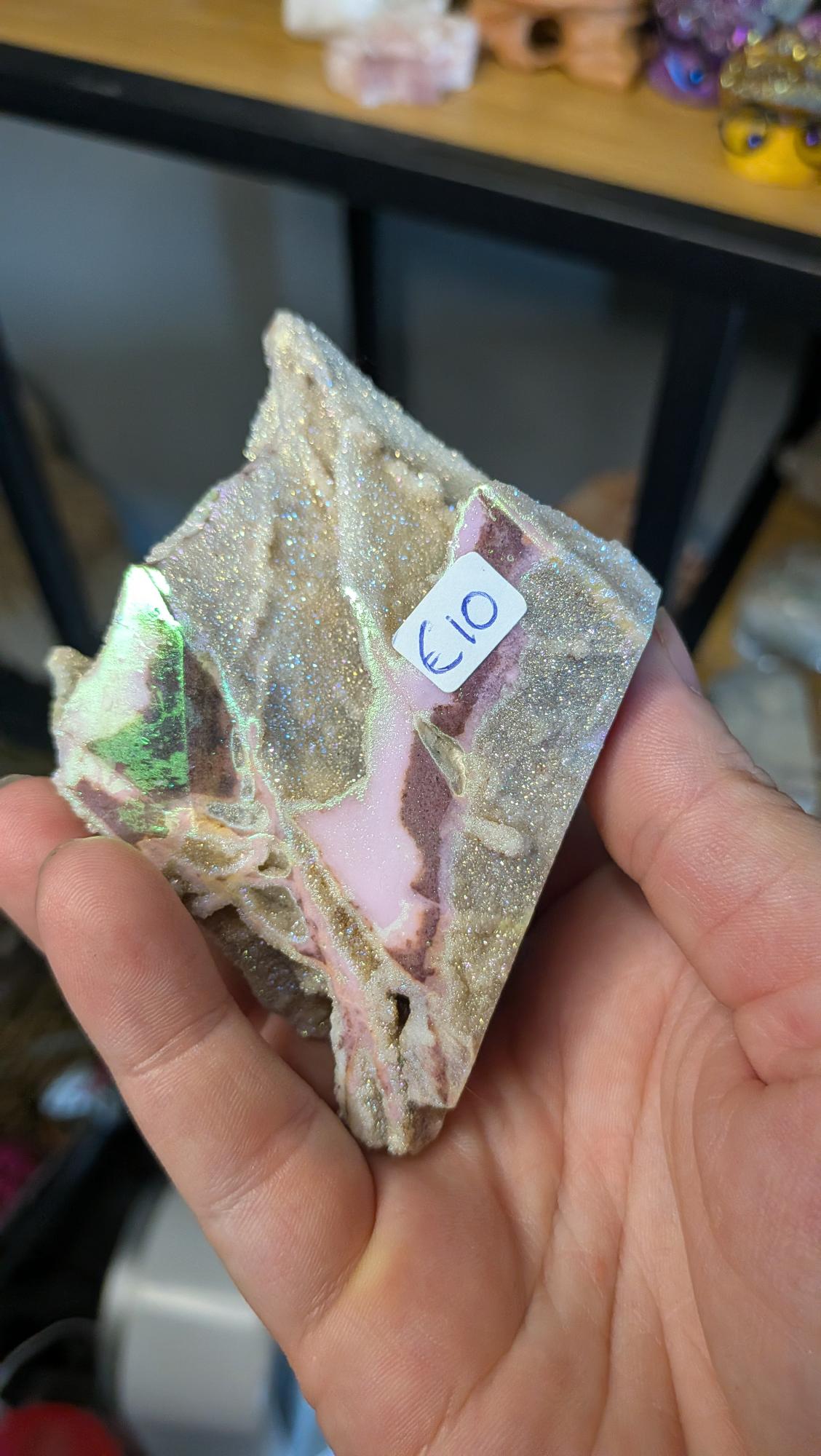 Close-up van de achterzijde van een aura sphaleriet specimen met roze texturen en een artikelnummersticker.